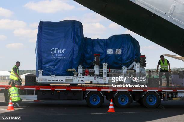 Workers maneuver a GEnx jet engine, manufactured by General Electric Co, as part of a cargo loading demonstration onto a Volga-Dnepr Group air cargo...