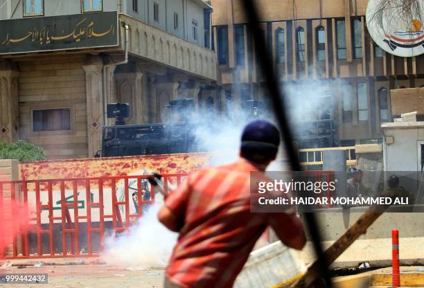 Iraqi riot police fire tear gas at protesters during a demonstration in Basra on July 15, 2018. - Dozens of demonstrators were wounded in southern...