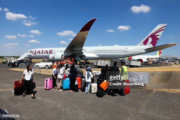 Passengers stand with their luggage after arriving on a Airbus SE A350 passenger aircraft, operated by Qatar Airways, during preparations ahead of...