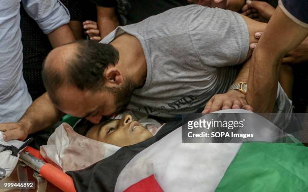 Father seen kissing the forehead of his child as a sign of farewell. Relatives and mourners bid farewell to the bodies of Palestinian teenagers Amir...