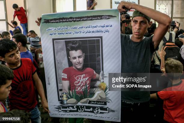 Palestinian carrying the image of the child martyr Luay Mazen Kahil during his farewell. Relatives and mourners bid farewell to the bodies of...