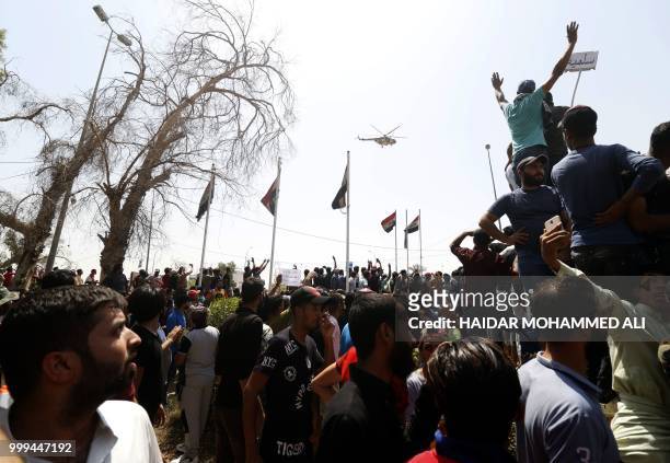 Iraqi protesters chant slogans and hold up signs during a demonstration in Basra on July 15, 2018. The arabic sign at top right reads:"peaceful." -...