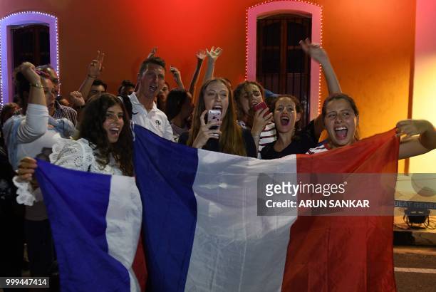 French football fans pose for a picture with the France national flag ahead of the FIFA 2018 World Cup final match between France and Croatia in...