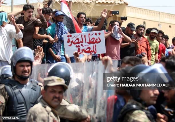 Iraqi security forces form a human barrier as protesters demonstrate against unemployment and a lack of basic services in the southern Iraqi city of...