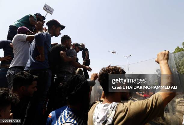 Iraqi protesters chant slogans and hold up signs during a demonstration in Basra on July 15, 2018. The arabic sign at top left reads:"peaceful." -...