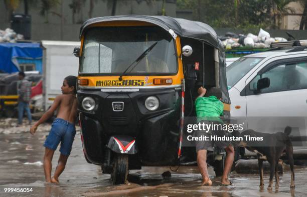 Boys push an auto that is stuck due to waters of high tide waves at Versova beach, on July 14, 2018 in Mumbai, India. Mumbaikars had to face another...