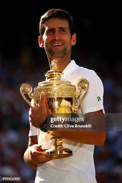 Novak Djokovic of Serbia celebrates with the trophy after winning the Men's Singles final against Kevin Anderson of South Africa on day thirteen of...