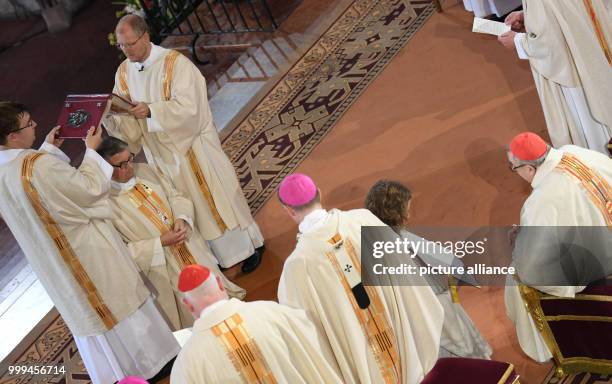 The Holy Gospel is being held above the head of Peter Kohlgraf in the presence of Cardinal Karl Lehmann during his episcopal ordination in the...