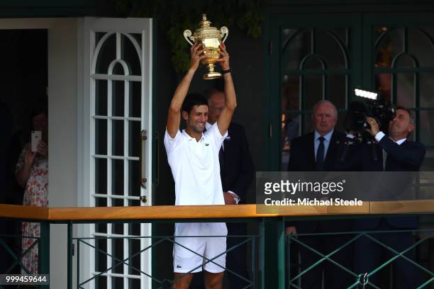 Novak Djokovic of Serbia lifts the trophy on the balcony of Centre Court after winning the Men's Singles final against Kevin Anderson of South Africa...