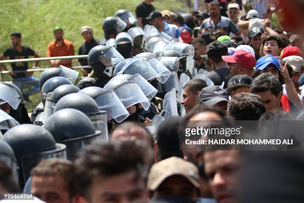 Iraqi security forces form a human barrier as protesters demonstrate against unemployment and a lack of basic services in the southern Iraqi city of...