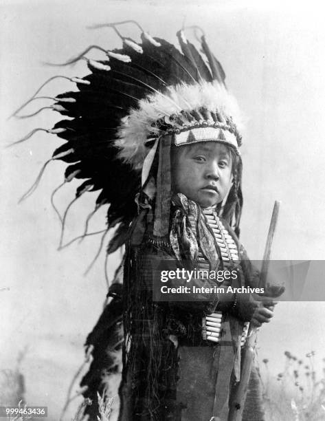 Portrait of a Native American boy from the Cheyenne tribe wearing feathered headdress, circa 1907.