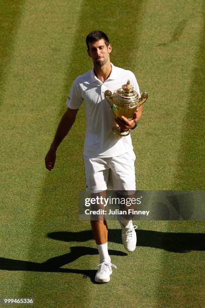 Novak Djokovic of Serbia celebrates with the trophy after winning the Men's Singles final against Kevin Anderson of South Africa on day thirteen of...