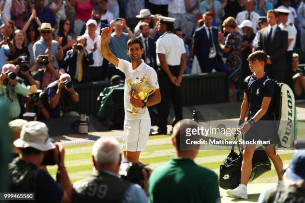 Novak Djokovic of Serbia looks back towards his players' box as he celebrates with the trophy after winning the Men's Singles final against Kevin...
