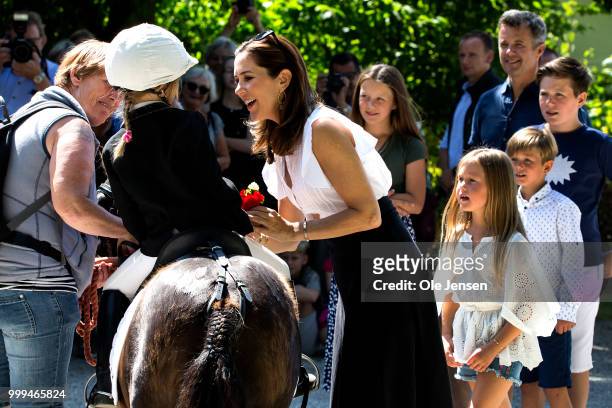 Crown Princess Mary of Denmark receives a flower bouquet from a small rider during the Tilting-At-The-Ring Riders Event at Graasten Castle at...