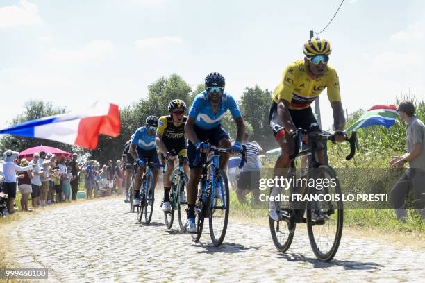Belgium's Greg Van Avermaet , wearing the overall leader's yellow jersey, and other riders pedal the stage's fifth cobblestone section between Tilloy...