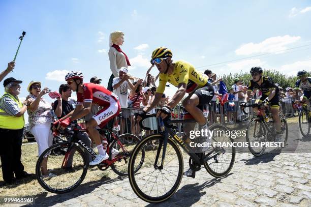 Belgium's Greg Van Avermaet , wearing the overall leader's yellow jersey, rides through the stage's first cobblestone section in Thun-l'Eveque during...