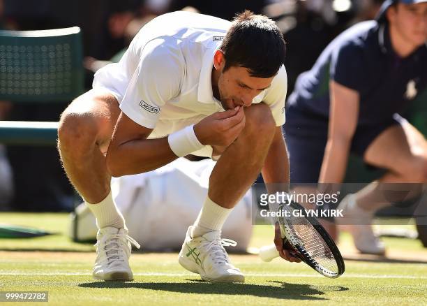 Serbia's Novak Djokovic eats some grass from the court as he celebrates after beating South Africa's Kevin Anderson 6-2, 6-2, 7-6 in their men's...
