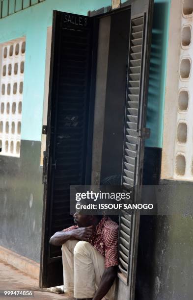 This picture taken on July 14, 2018 shows a man who found shelter at a school after their neighbourhood was flooded duribg heavy rainfall in Aboisso,...