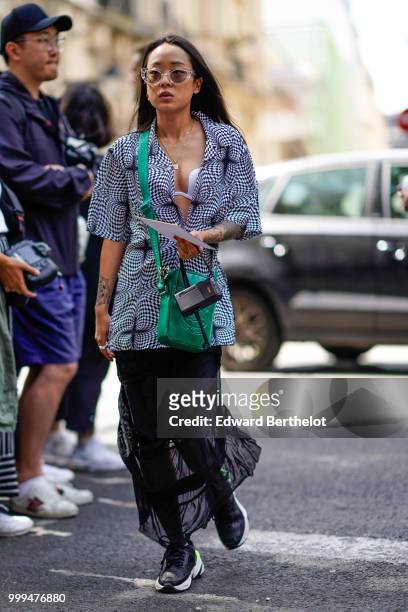 Christina Paik wears a green bag, a black and white jacket, a black lace skirt, black sneakers, outside Wooyoungmi, during Paris Fashion Week -...