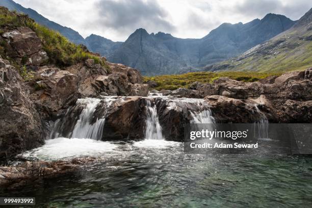 waterfall at the fairy pools in glen brittle with cuillin hills behind, isle of skye, scotland, united kingdom - cuillins stockfoto's en -beelden