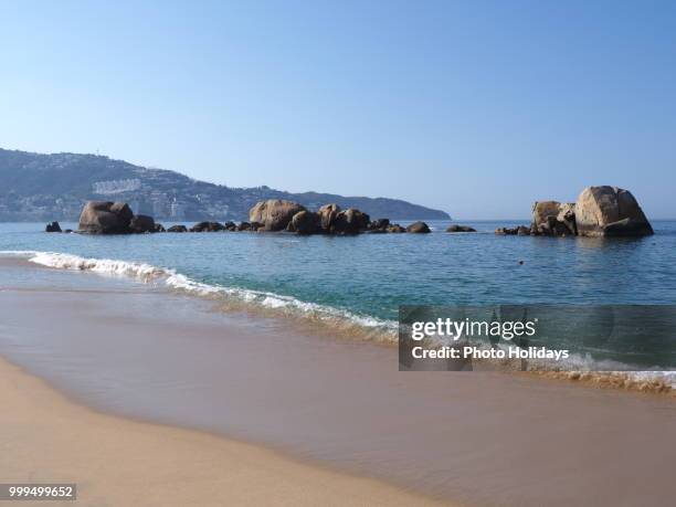 scenic panorama of rocks at bay of acapulco city in mexico, pacific ocean waves on sandy beach... - city beach imagens e fotografias de stock