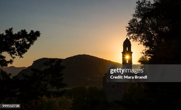 sun shining through a belfry, silhouette of a church tower, evening mood, sunset, haute-corse, corsica, france - haute corse stock-fotos und bilder