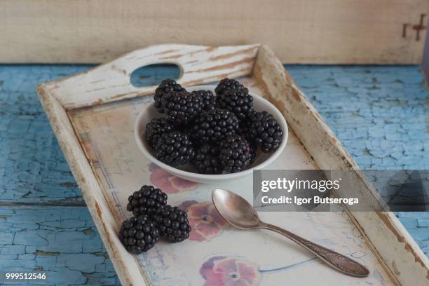 blackberry in the white bowl with a spoon on the wooden tray - blackberry stock-fotos und bilder