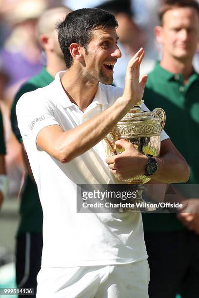 Mens Singles Final - Novak Djokovic v Kevin Anderson - Novak Djokovic waves to his wife and son as he holds the winners trophy at All England Lawn...