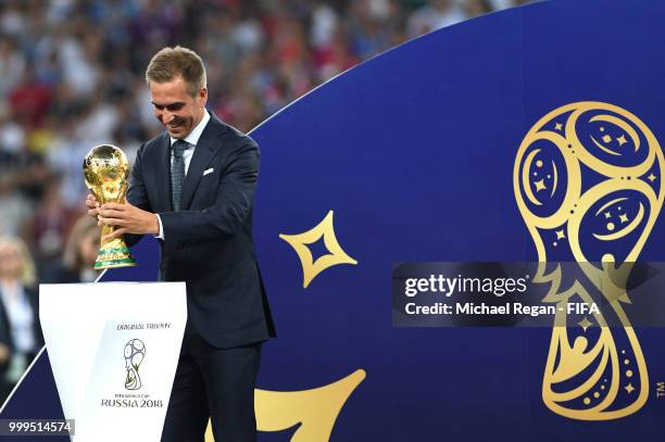 Former football player Philippe Lahm takes the World Cup trophy on the stage for the winning ceremony following the 2018 FIFA World Cup Final between...