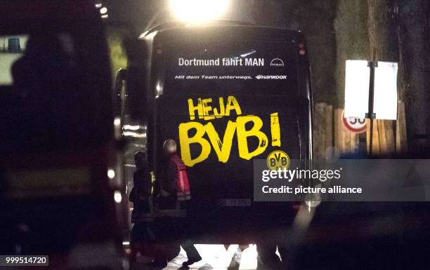 Firefighters walk past the team bus of the soccer team of Borussia Dortmund, close to which three explosions occured in the evening in Dortmund,...