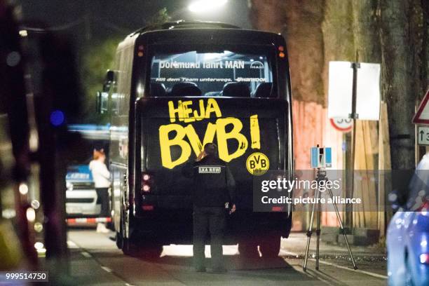 An officer of State Office of Criminal Investigation investigates the team bus of the soccer team of Borussia Dortmund, close to which three...