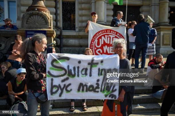 Demonstrators hold up a banner with partially incorrect Polish translating into 'A different world should be possible' in front of the criminal...
