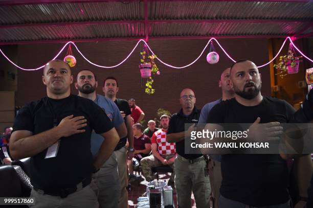 Croatian soldiers from the NATO coalition stands for their national anthem during a live broadcast of the final FIFA World Cup match between France...