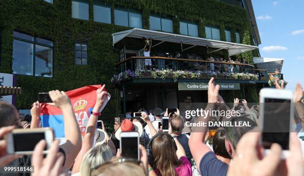 Serbia's Novak Djokovic holds up the winners trophy on the balcony of centre court after beating South Africa's Kevin Anderson 6-2, 6-2, 7-6 in their...