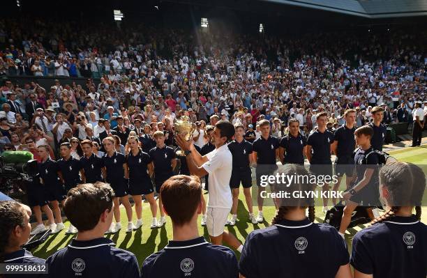 Serbia's Novak Djokovic holds the winners trophy as he leaves centre court after beating South Africa's Kevin Anderson 6-2, 6-2, 7-6 in their men's...