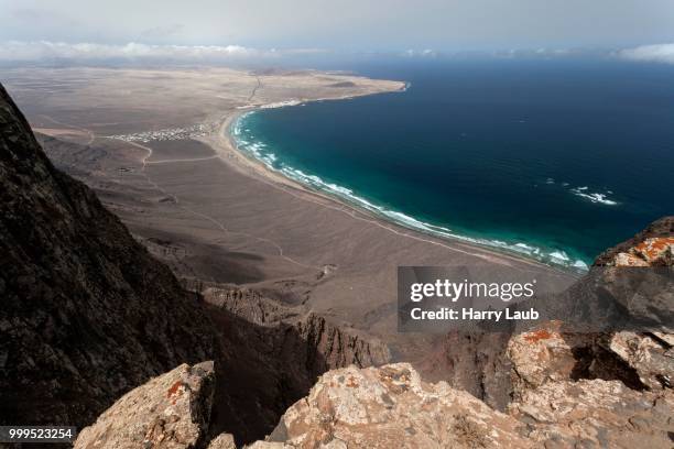 view from mirador del bosquecillo, risco de famara, on famara beach or playa de famara with la calaeta and famara resort, lanzarote, canary islands, spain - mirador stock pictures, royalty-free photos & images