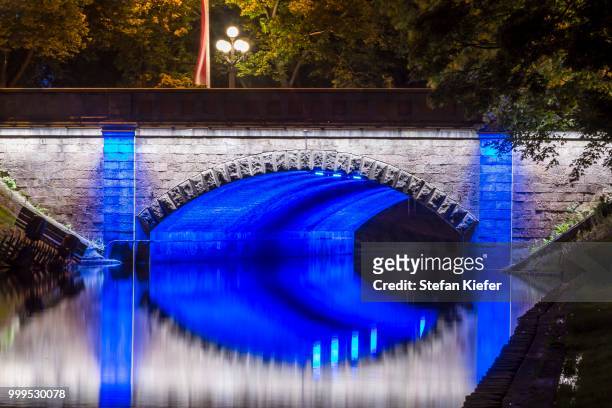 illuminated bridge along the pilsetas canal, riga, latvia - kiefer foto e immagini stock