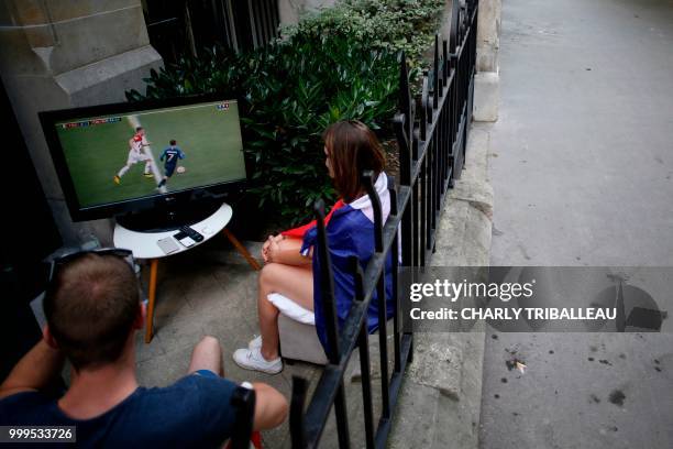 People sit in their courtyard and watch the Russia 2018 World Cup final football match between France and Croatia, in Paris on July 15, 2018.