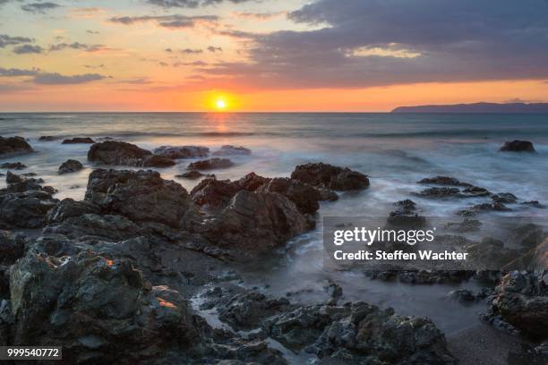 sunset on the pacific coast, water washing over rocks, osa peninsula at the rear, golfo dulce, puntarenas province, costa rica - osa peninsula stockfoto's en -beelden