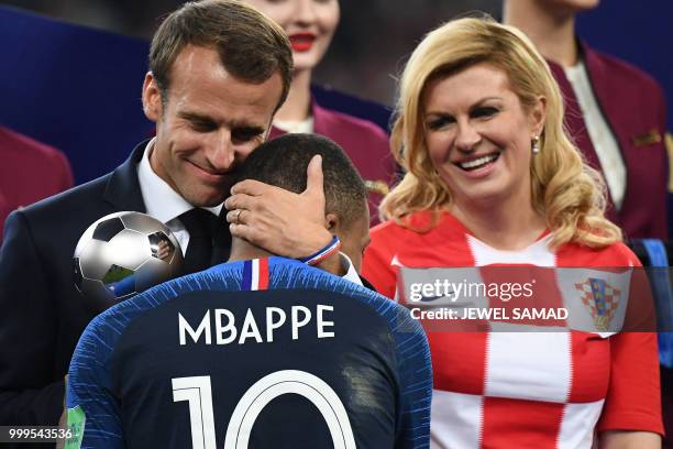 French President Emmanuel Macron hugs France's forward Kylian Mbappe as he presents him with the Best Young Player Award after the Russia 2018 World...