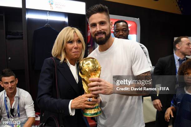 Wife of French President Emmanuel Macron, Brigitte Macron, and Olivier Giroud of France pose for a photo with the World Cup Trophy in the dressing...