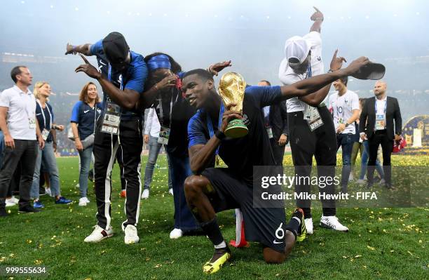 Paul Pogba of France celebrates with his family and the World Cup Trophy following his sides victory in the 2018 FIFA World Cup Final between France...