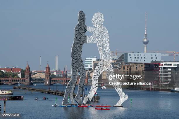 Canoe glides by the large art sculptures made from aluminum while several new buildings and construction sites can be seen in the background, in...