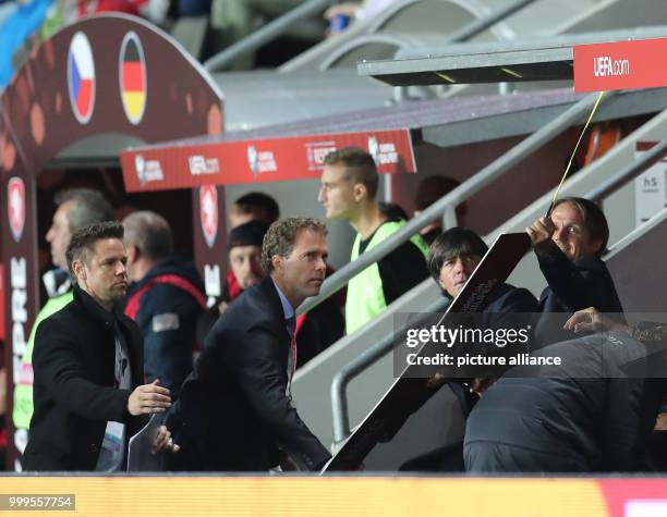 Germany's assistant coach Thomas Schneider holds a UEFA sign which has come off the coach's bench, with Germany's head coach Joachim Loew looking on...