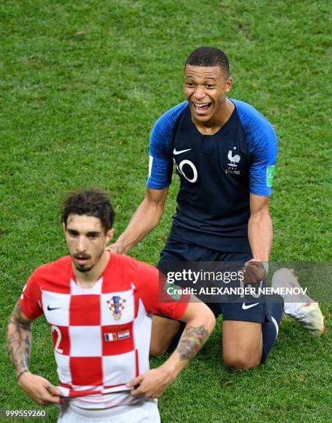 France's forward Kylian Mbappe celebrates next to Croatia's defender Sime Vrsaljko after winning at the end the Russia 2018 World Cup final football...