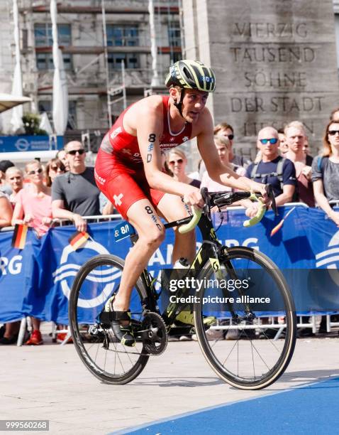 July 2018, Germany, Hamburg: Adrien Briffod from Switzerland riding his bicycle across the Rathausmarkt during the Triathlon Mixed Relay World...