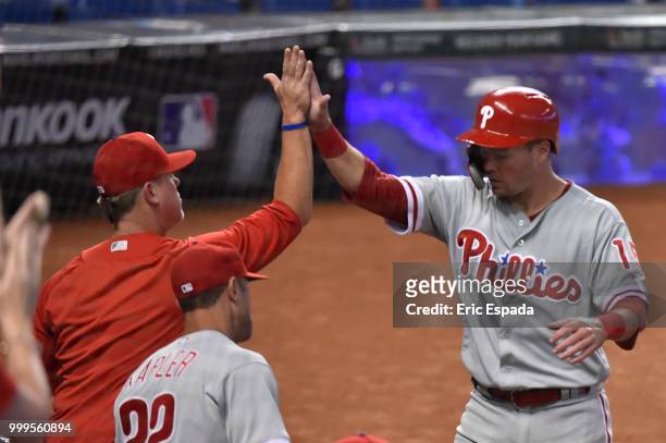 Andrew Knapp of the Philadelphia Phillies high fives Hitting Coach John Mallee after scoring in the fourth inning against the Miami Marlins at...