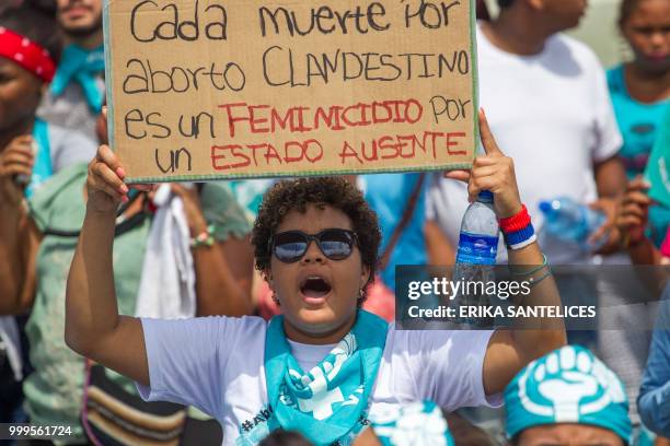 Woman holds a sign reading "Each death caused by clandestine abortion is a femicide of the absent state" as she takes part in a march for the...