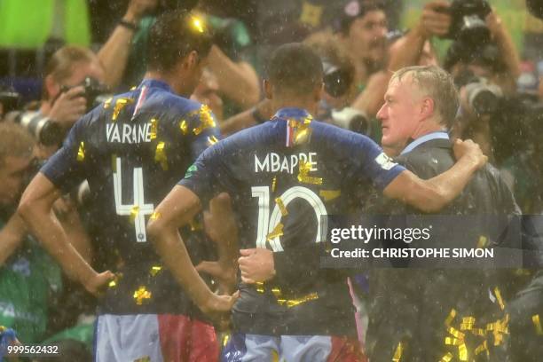 France's defender Raphael Varane and France's forward Kylian Mbappe celebrate with France's coach Didier Deschamps at the end of the Russia 2018...