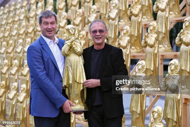 The concept artist Ottmar Hoerl and the Bavarian minister of homeland affairs Markus Soeder stand between golden Madonna figurines in Nuremberg,...